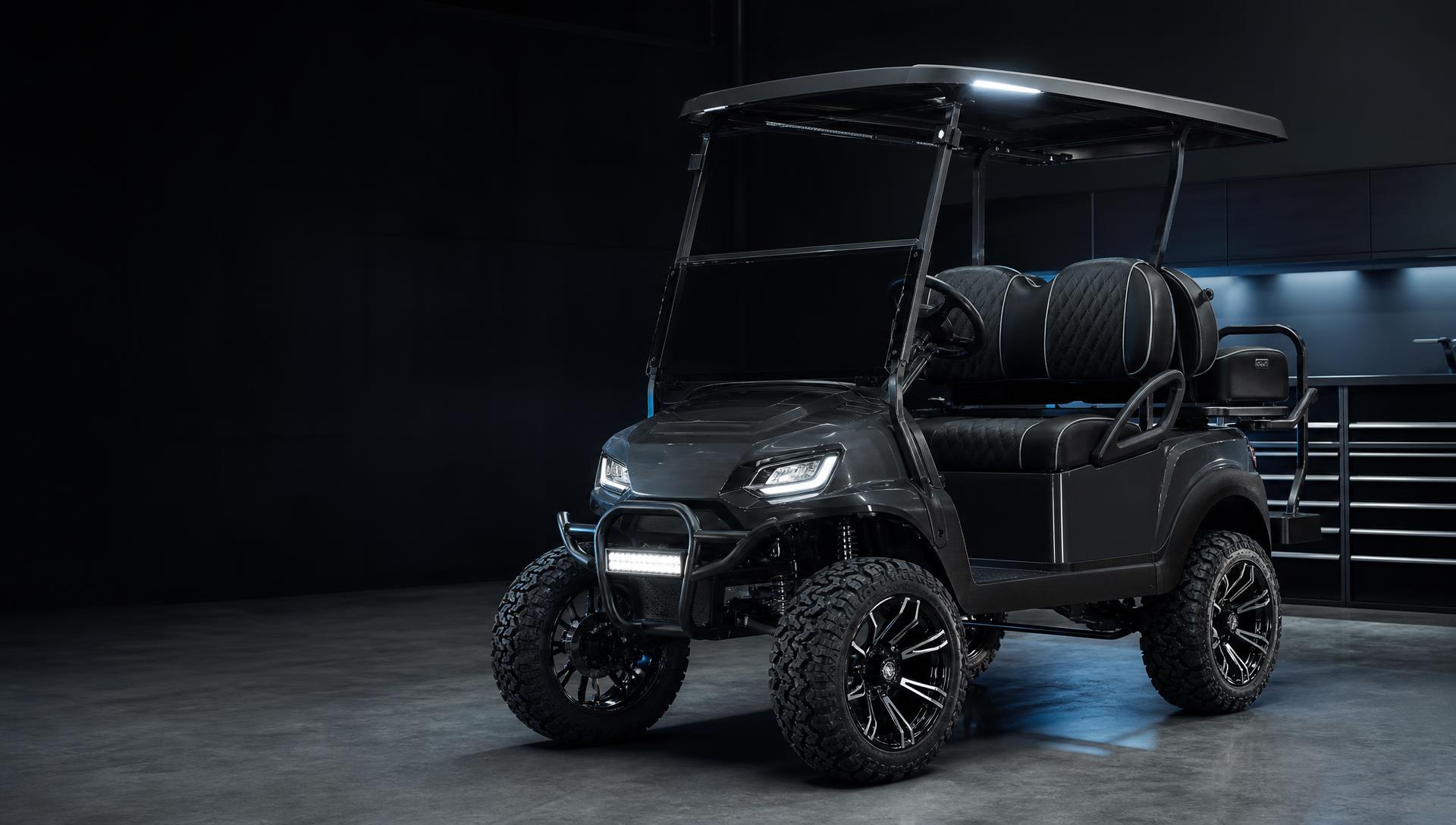 Lifted custom golf cart with premium wheels and LED lighting in a dark upscale workshop